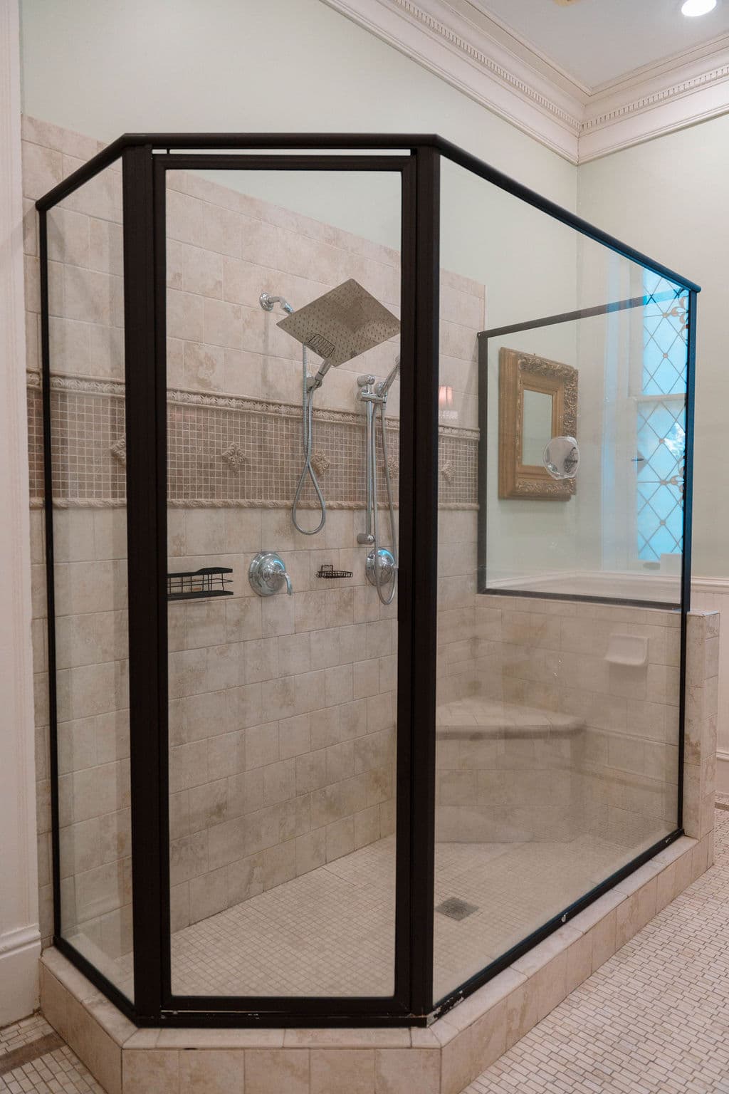 Large glass-enclosed walk-in shower featuring beige tile, a built-in corner bench, and a modern rainfall showerhead.