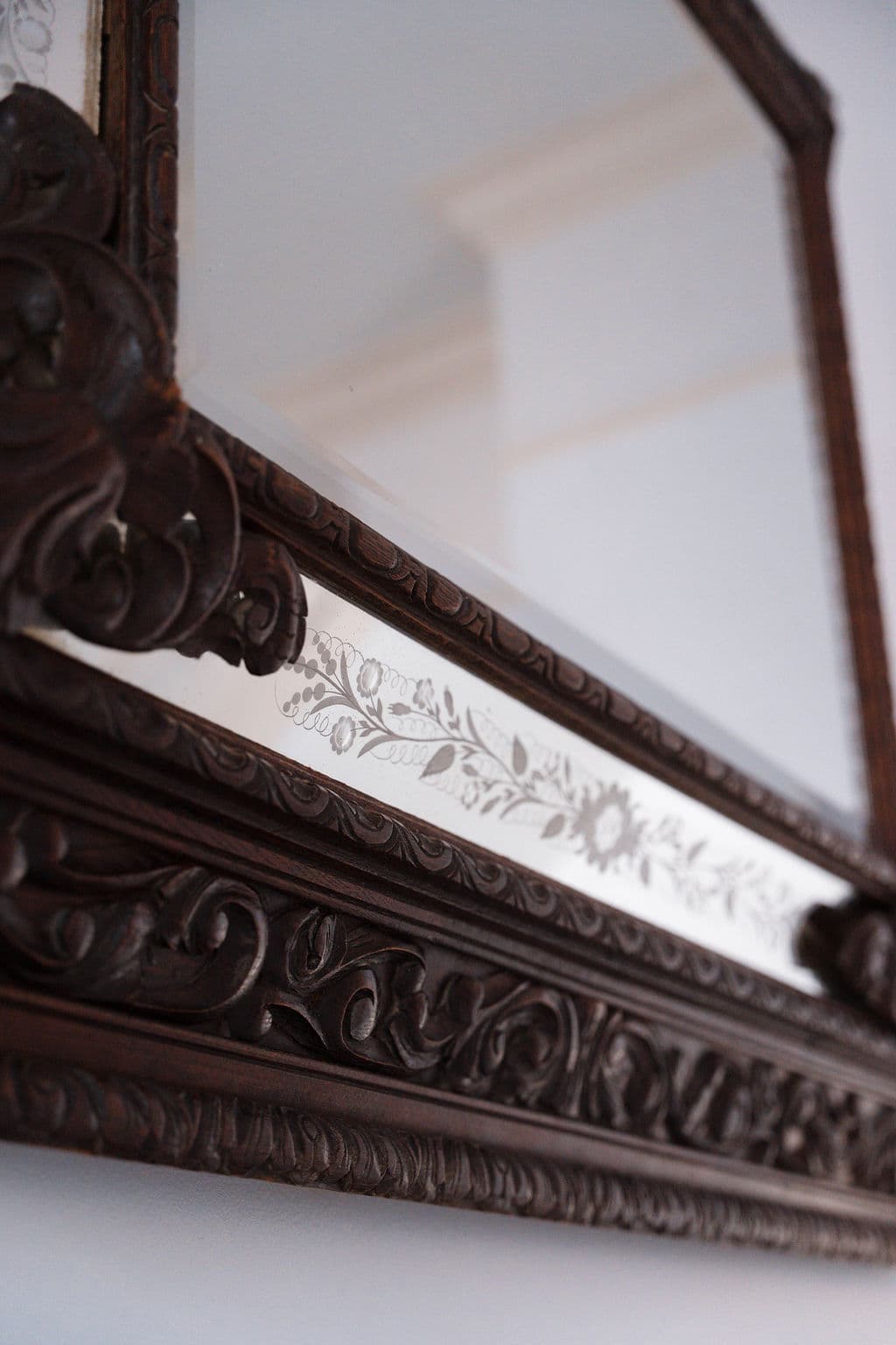 Detail of ornate carved wood mirror frame with etched glass accents.