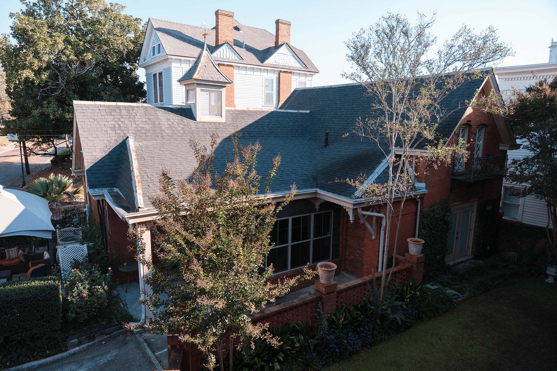 Aerial view of two residential buildings surrounded by lush greenery in a sunny neighborhood.